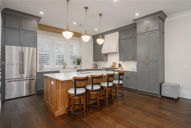 kitchen featuring a kitchen island, sink, hanging light fixtures, stainless steel appliances, and custom range hood