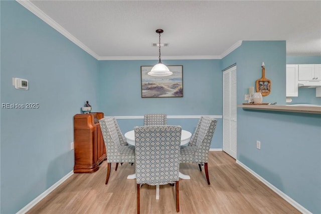 dining room with ornamental molding and light wood-type flooring