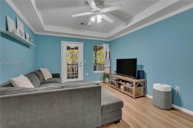 living room featuring ceiling fan, light hardwood / wood-style floors, and a tray ceiling