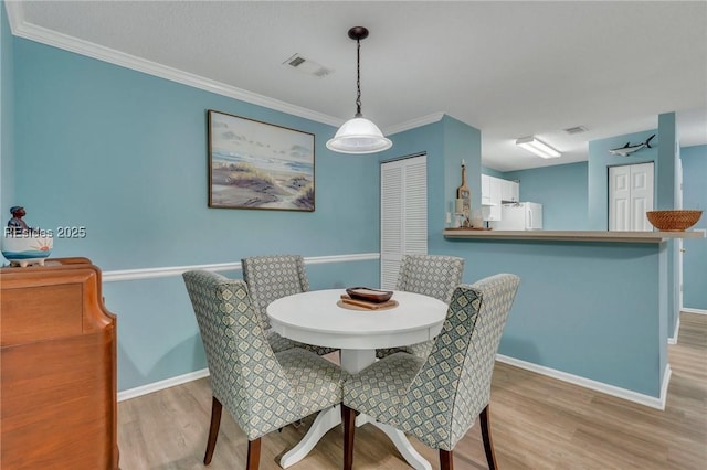 dining room featuring ornamental molding and light hardwood / wood-style flooring