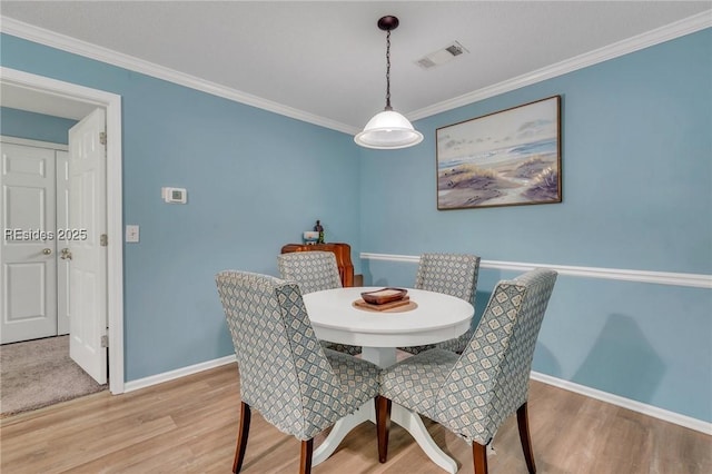 dining area with crown molding and light hardwood / wood-style flooring