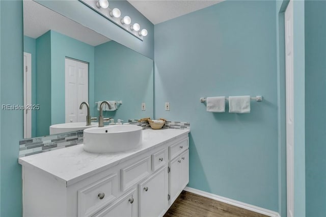 bathroom with vanity, hardwood / wood-style floors, a textured ceiling, and decorative backsplash