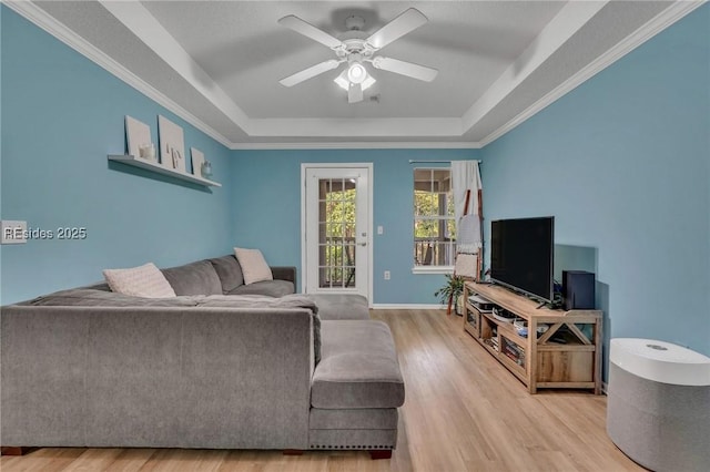 living room with light hardwood / wood-style flooring, a raised ceiling, and ceiling fan