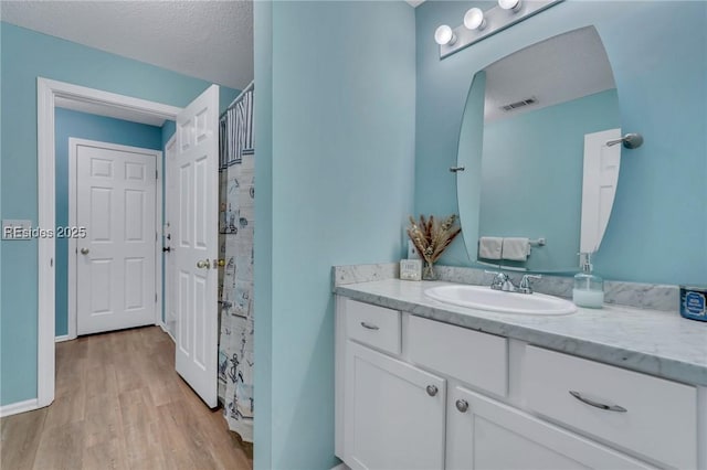 bathroom with vanity, hardwood / wood-style floors, a textured ceiling, and a shower with shower curtain