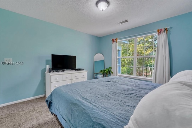 bedroom featuring light colored carpet and a textured ceiling