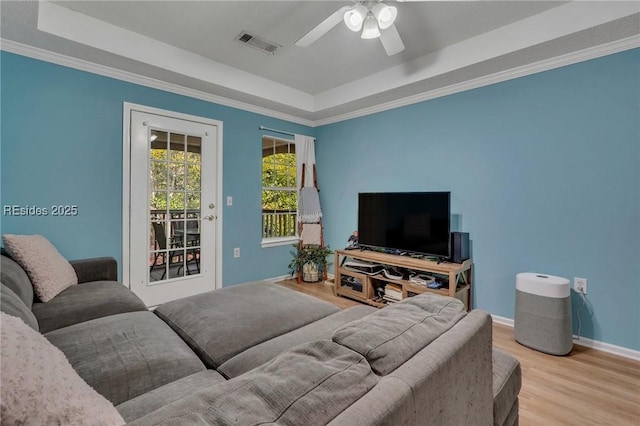 living room featuring a raised ceiling, ceiling fan, and light hardwood / wood-style floors