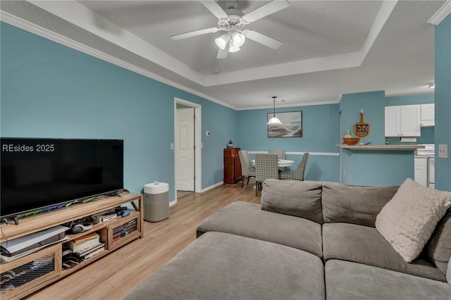 living room with crown molding, light hardwood / wood-style floors, a raised ceiling, and ceiling fan