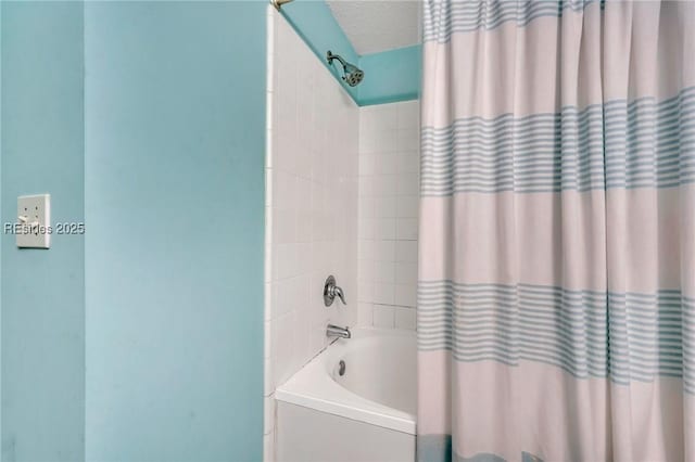 bathroom with shower / bath combo with shower curtain and a textured ceiling