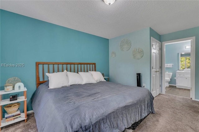 carpeted bedroom featuring a textured ceiling and ensuite bath