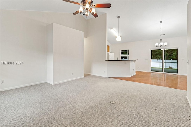 unfurnished living room with ceiling fan with notable chandelier, light colored carpet, and high vaulted ceiling