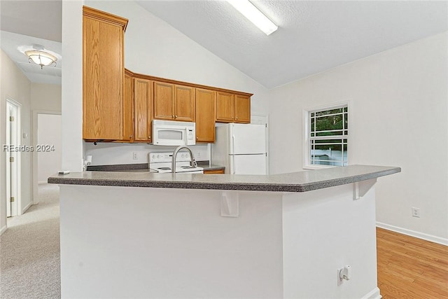 kitchen with white appliances, a breakfast bar, and kitchen peninsula