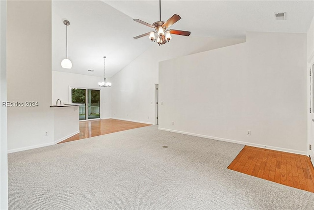 carpeted empty room with lofted ceiling and ceiling fan with notable chandelier