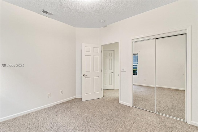 unfurnished bedroom featuring carpet floors, a textured ceiling, and a closet