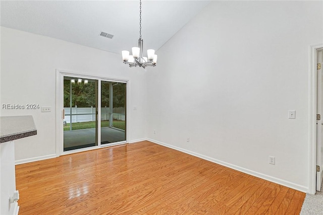 spare room with wood-type flooring and a chandelier