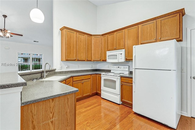 kitchen featuring sink, decorative light fixtures, light wood-type flooring, kitchen peninsula, and white appliances