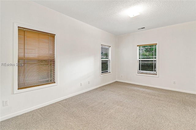 carpeted empty room featuring a textured ceiling