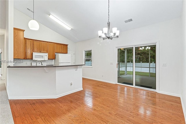 kitchen featuring white appliances, decorative light fixtures, a breakfast bar, and light hardwood / wood-style floors