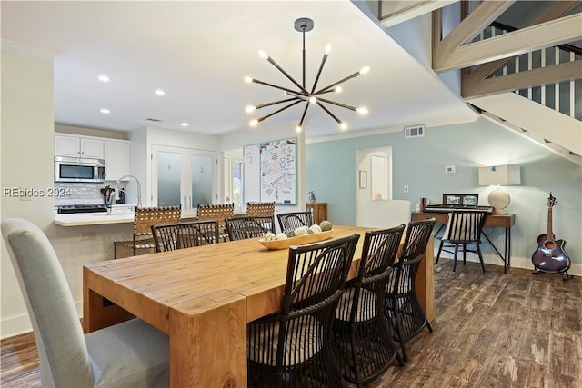 dining space with a notable chandelier, dark wood-type flooring, ornamental molding, and french doors