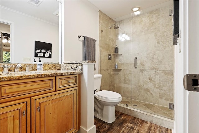 bathroom featuring hardwood / wood-style floors, vanity, toilet, a shower with door, and crown molding