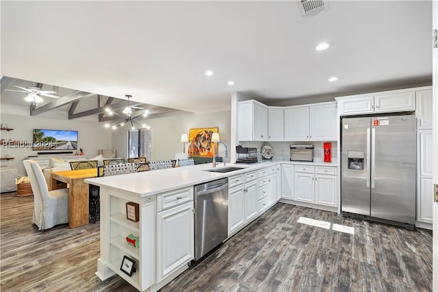 kitchen with pendant lighting, beamed ceiling, sink, kitchen peninsula, and stainless steel appliances