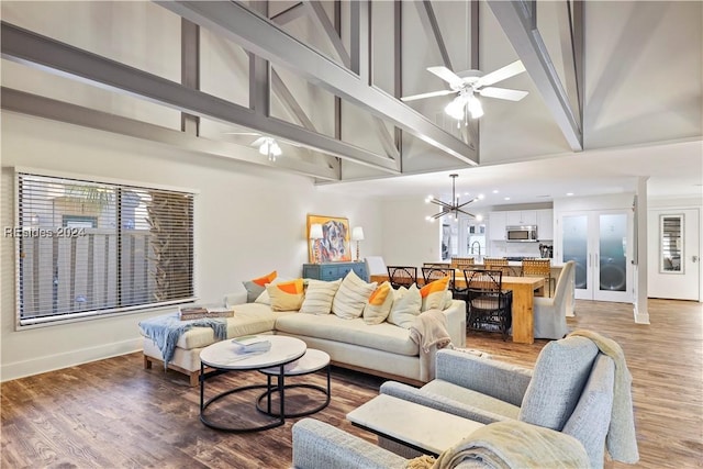 living room featuring wood-type flooring, plenty of natural light, ceiling fan with notable chandelier, and high vaulted ceiling