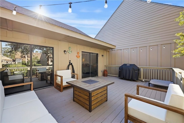 wooden deck with grilling area and an outdoor living space with a fire pit