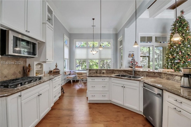 kitchen with pendant lighting, sink, white cabinetry, and appliances with stainless steel finishes