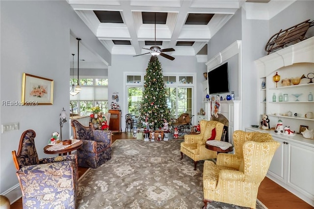 living room with dark wood-type flooring, coffered ceiling, crown molding, ceiling fan, and beam ceiling