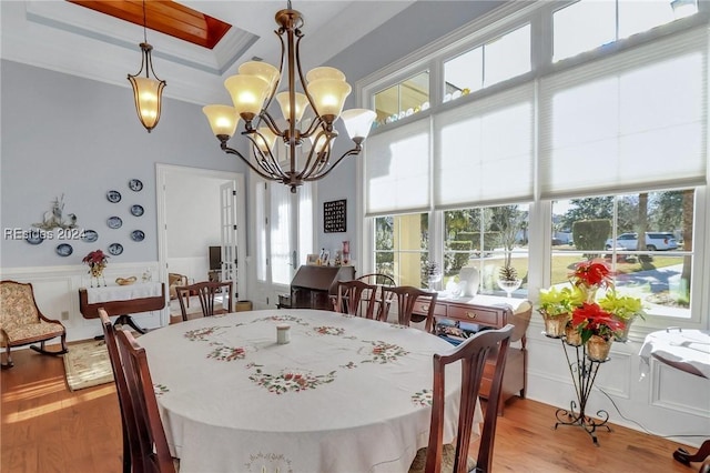 dining room with ornamental molding, a healthy amount of sunlight, light hardwood / wood-style flooring, and a notable chandelier