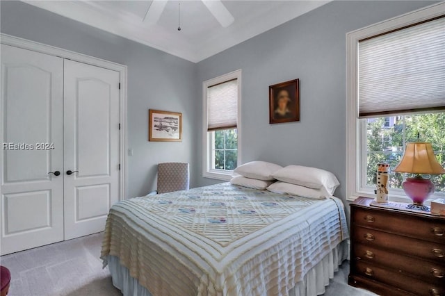 bedroom featuring light carpet, ceiling fan, and a closet