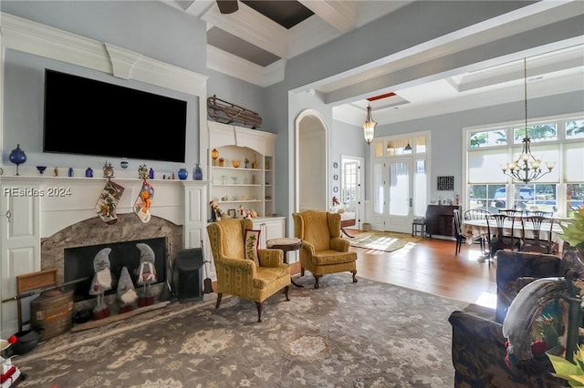 living room with beamed ceiling, wood-type flooring, crown molding, and an inviting chandelier