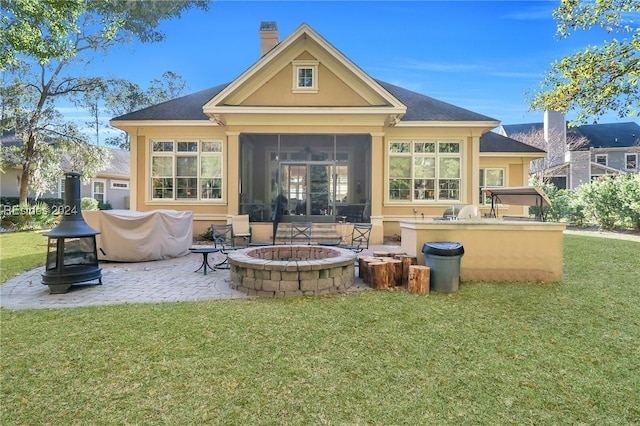 back of property with a sunroom, a patio area, a fire pit, and a lawn