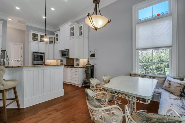 kitchen with white cabinetry, appliances with stainless steel finishes, decorative light fixtures, and dark wood-type flooring