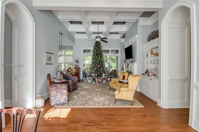 living room featuring ceiling fan, beam ceiling, coffered ceiling, wood-type flooring, and built in shelves