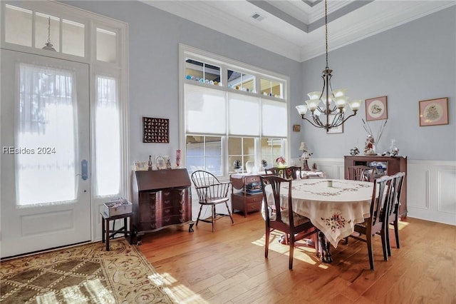 dining area with an inviting chandelier, a wealth of natural light, ornamental molding, and light hardwood / wood-style flooring