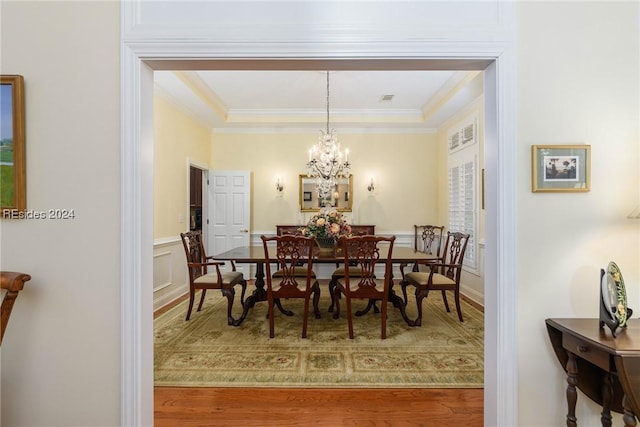 dining space with crown molding, wood-type flooring, and a chandelier