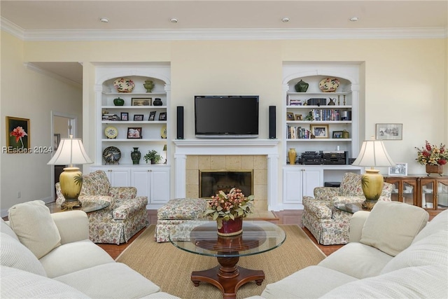 living room featuring built in shelves, ornamental molding, a tile fireplace, and light wood-type flooring