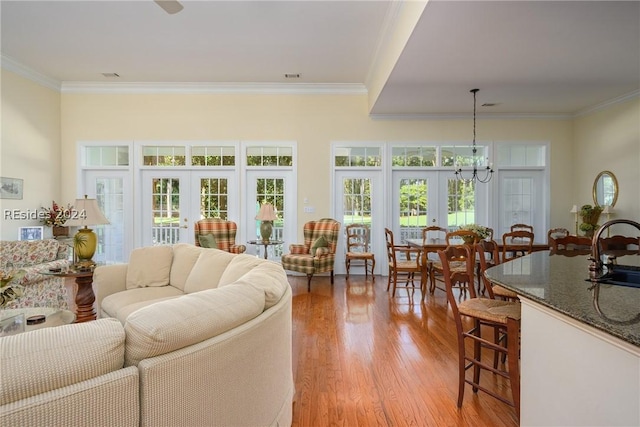 living room with sink, crown molding, light hardwood / wood-style floors, and french doors