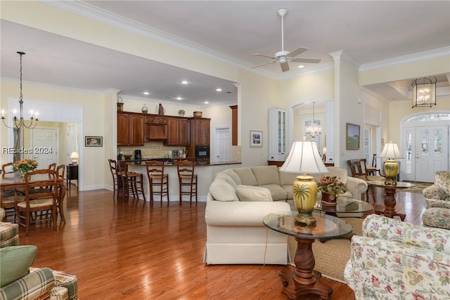 living room featuring hardwood / wood-style floors, ceiling fan with notable chandelier, and ornamental molding