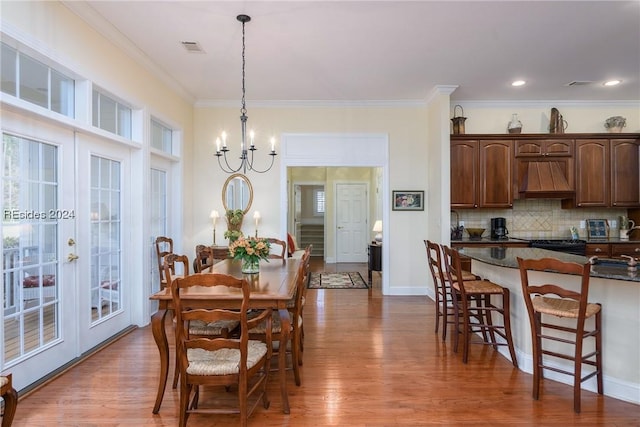 dining area featuring crown molding, wood-type flooring, a notable chandelier, and french doors