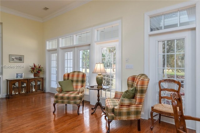 living area featuring hardwood / wood-style flooring and ornamental molding