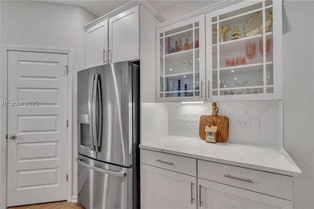 kitchen featuring white cabinetry, light hardwood / wood-style floors, light stone countertops, and stainless steel fridge with ice dispenser