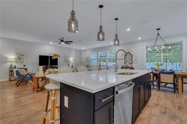 kitchen featuring a center island with sink, a breakfast bar area, stainless steel dishwasher, and light hardwood / wood-style flooring