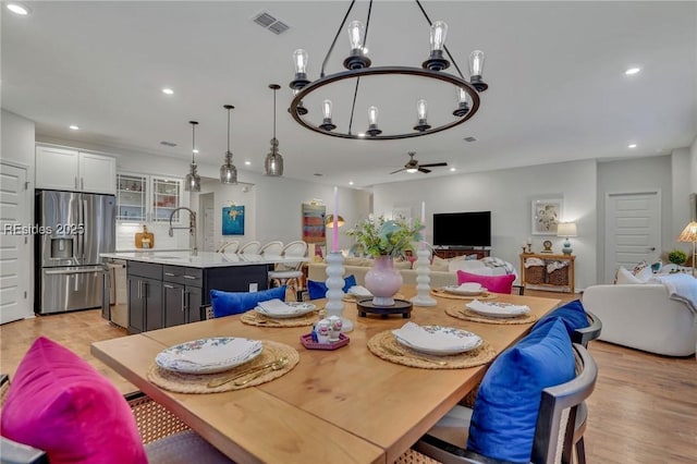 dining room featuring sink, ceiling fan with notable chandelier, and light hardwood / wood-style flooring