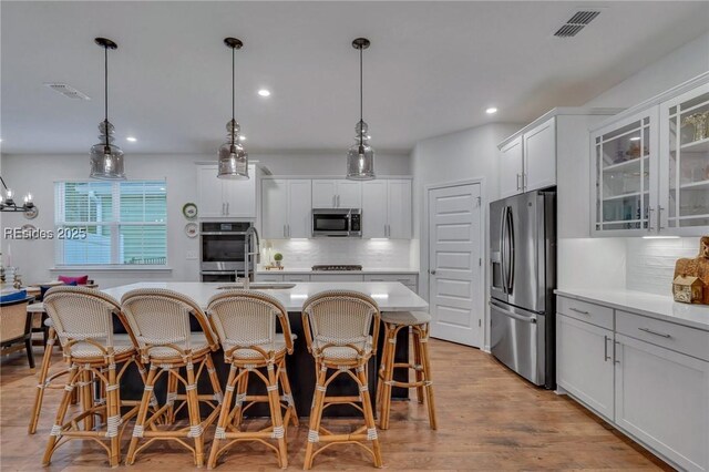 kitchen featuring white cabinetry, appliances with stainless steel finishes, hanging light fixtures, and backsplash