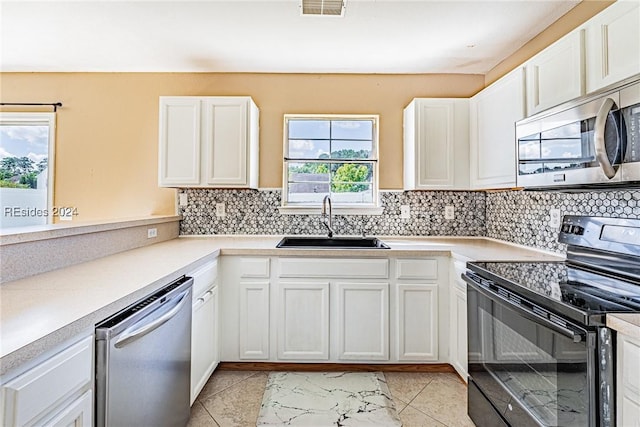 kitchen featuring light tile patterned floors, appliances with stainless steel finishes, sink, and white cabinets