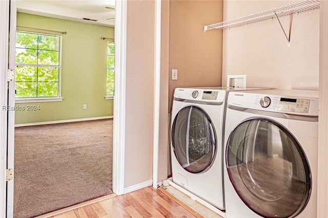 clothes washing area with independent washer and dryer and light hardwood / wood-style floors