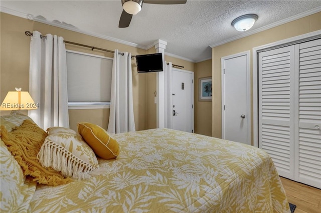 bedroom featuring ornamental molding, wood-type flooring, a textured ceiling, and ceiling fan