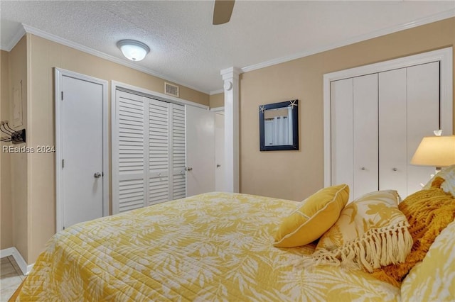 bedroom featuring ceiling fan, ornamental molding, a textured ceiling, and two closets