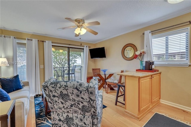 living room featuring crown molding, plenty of natural light, ceiling fan, and light wood-type flooring